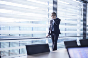 businessman making smartphone call and looking through office window