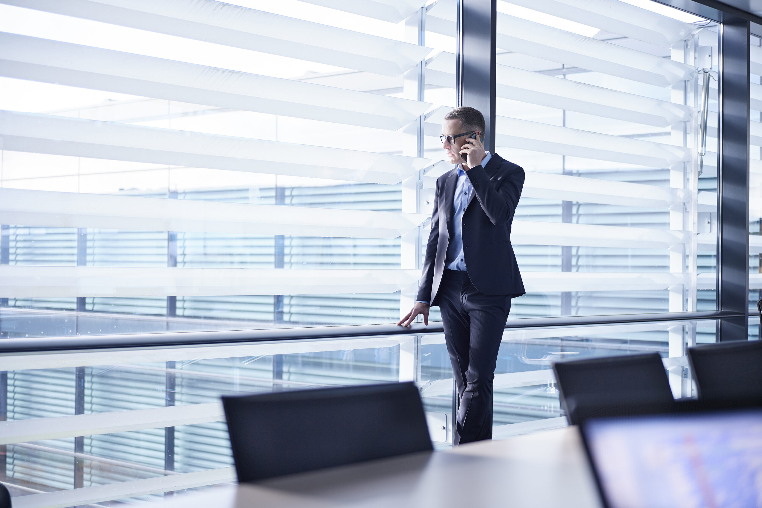 businessman making smartphone call and looking through office window